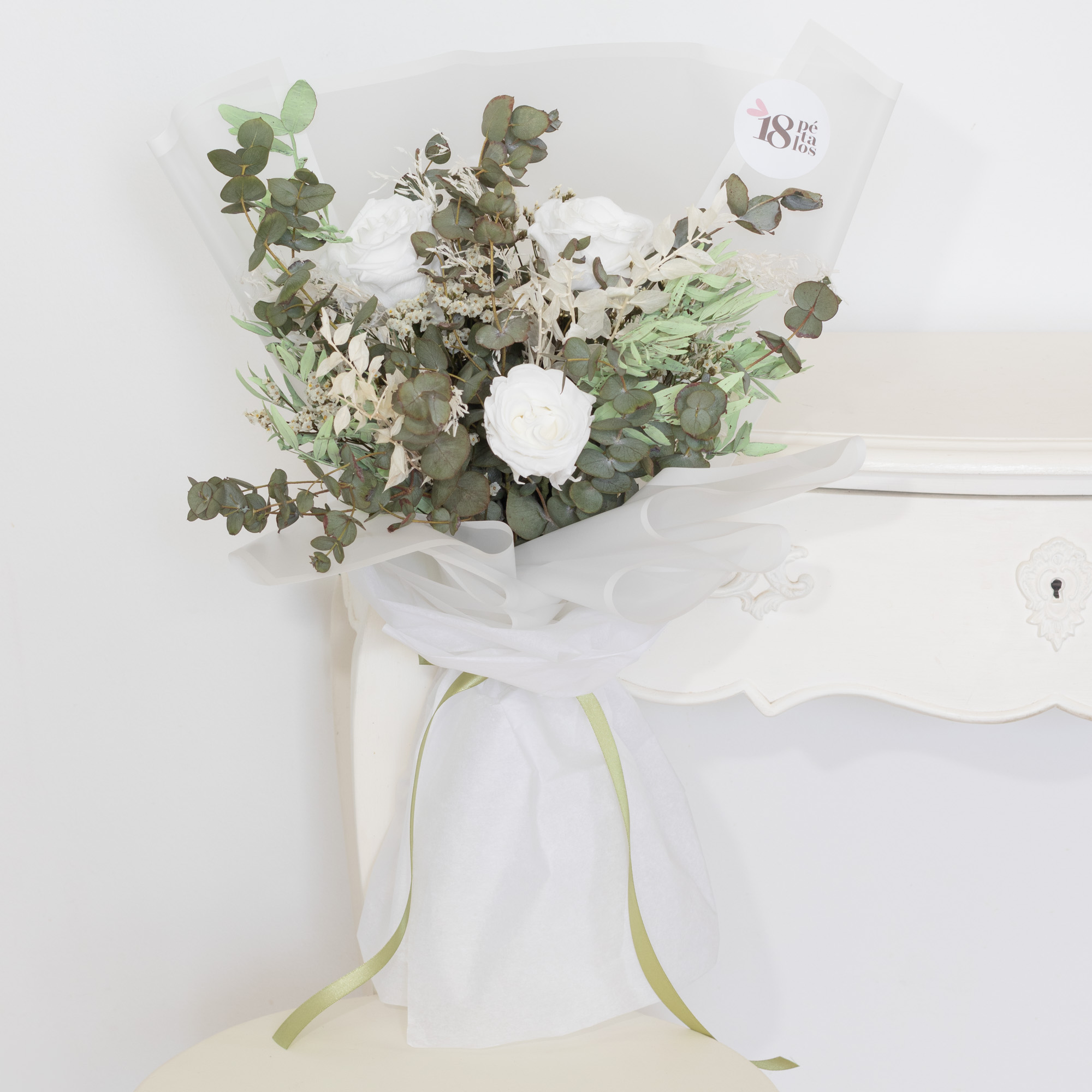 Ramo de rosas blancas preservadas con follaje verde y estilo natural sobre fondo claro