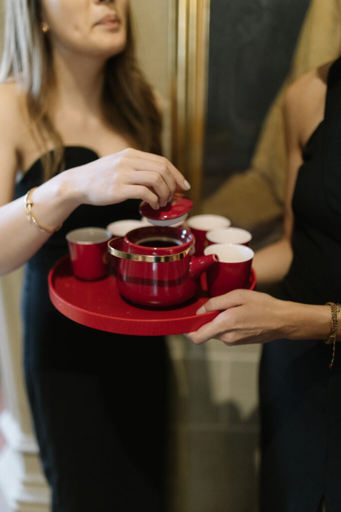 Detalle del juego de té nupcial chino: tetera y tazas lacadas en rojo y oro sobre bandeja, listas para la ceremonia del té en la boda